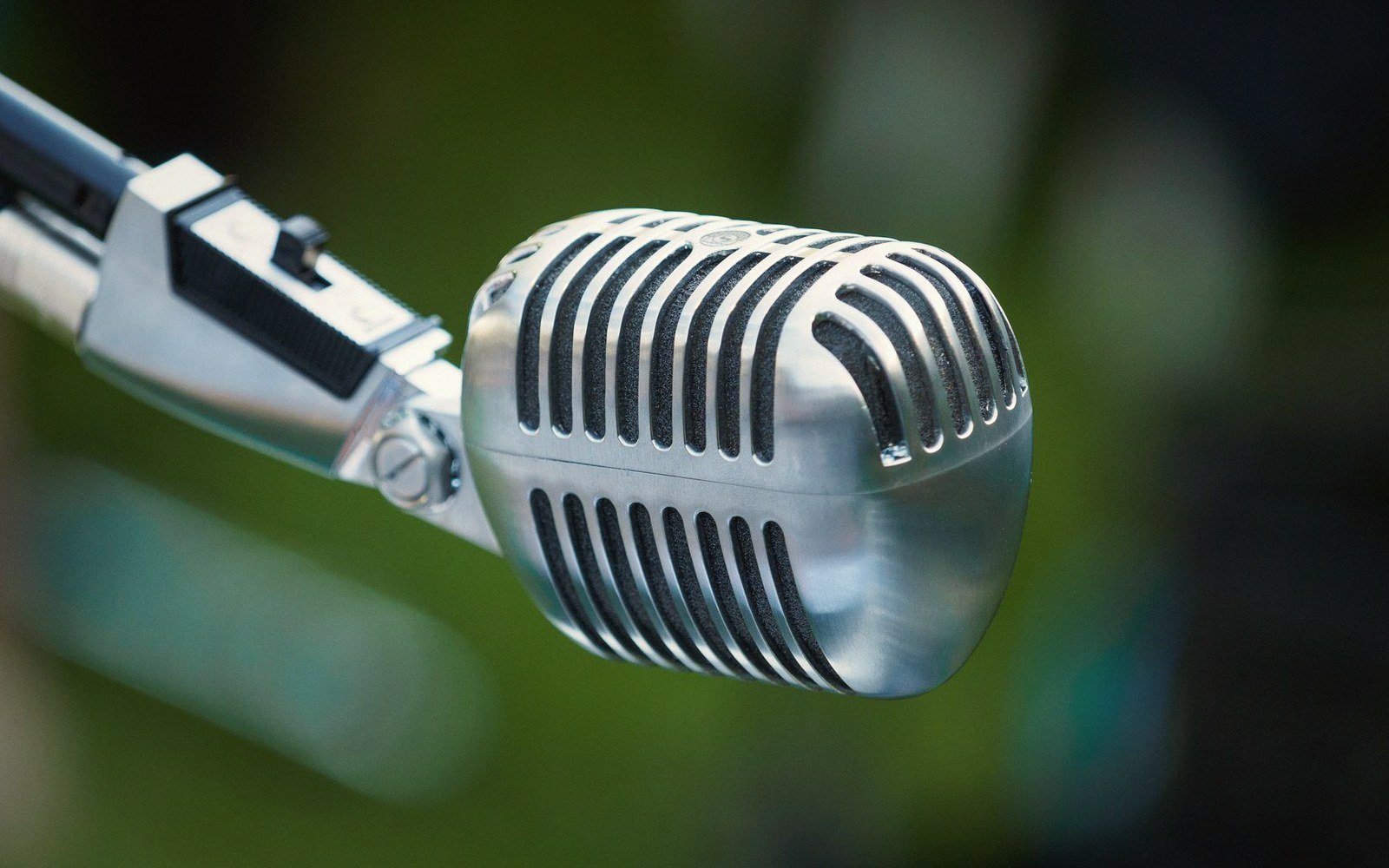 Close-up of a vintage chrome microphone mounted on a metal stand outdoors